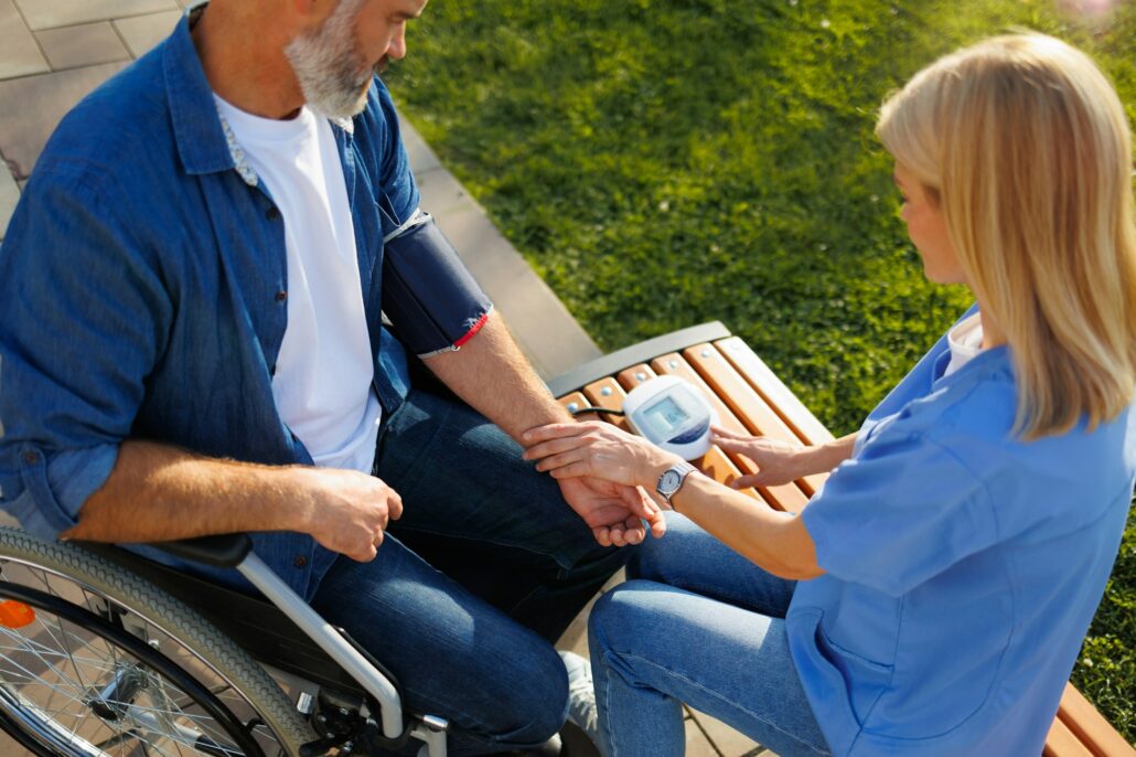 Community Health: Nurse Monitors Blood Pressure of Man in Wheelchair