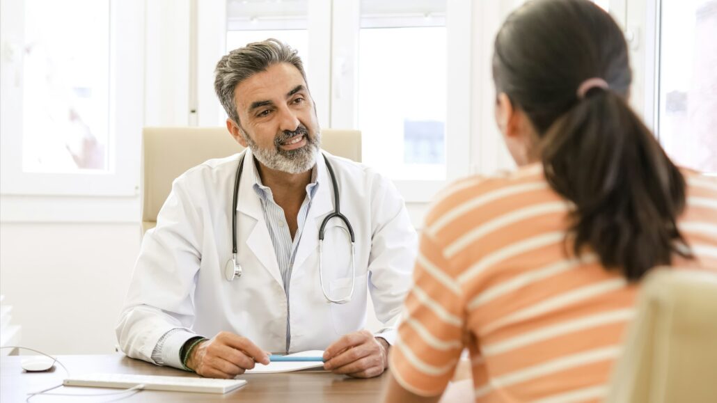 Happy male doctor talking to female patient in clinic