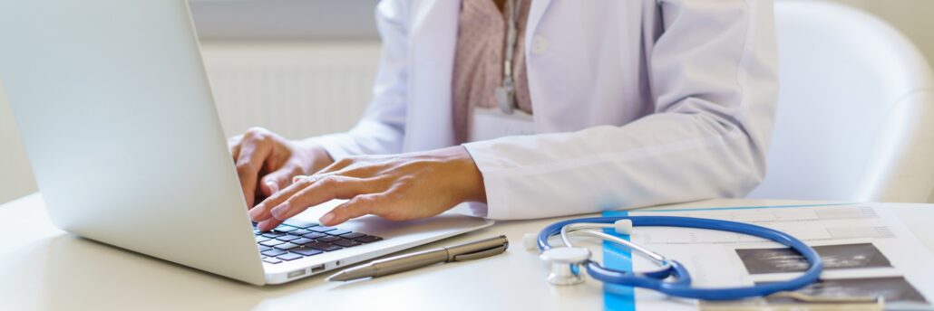 Panoramic banner with female doctor in white uniform working on laptop computer in hospital