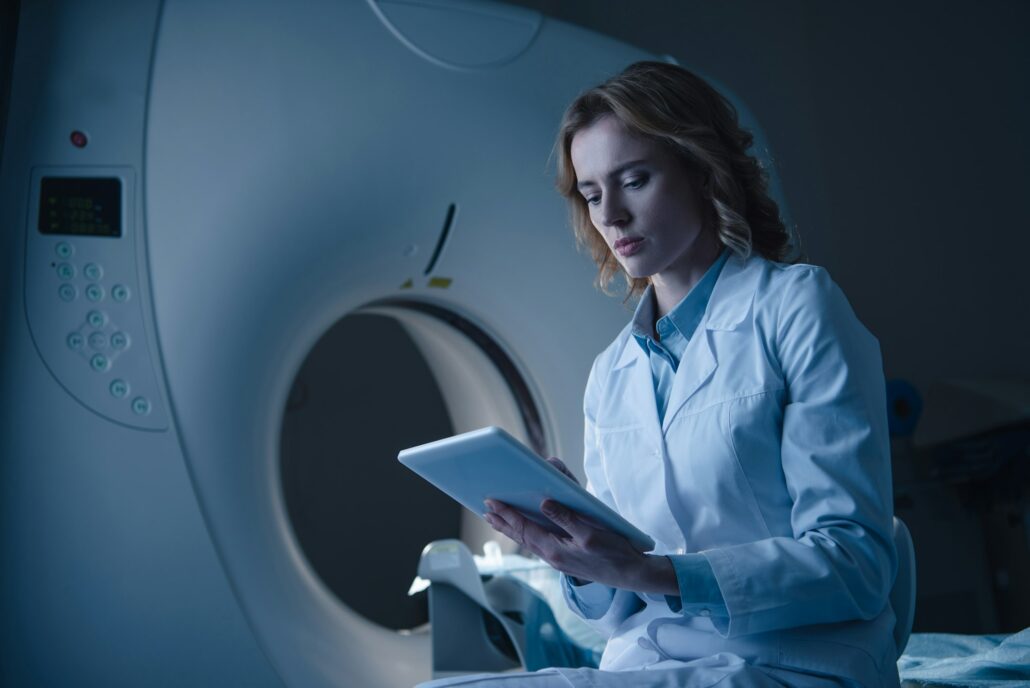 serious doctor looking at digital tablet with x-ray diagnosis while sitting near ct scanner