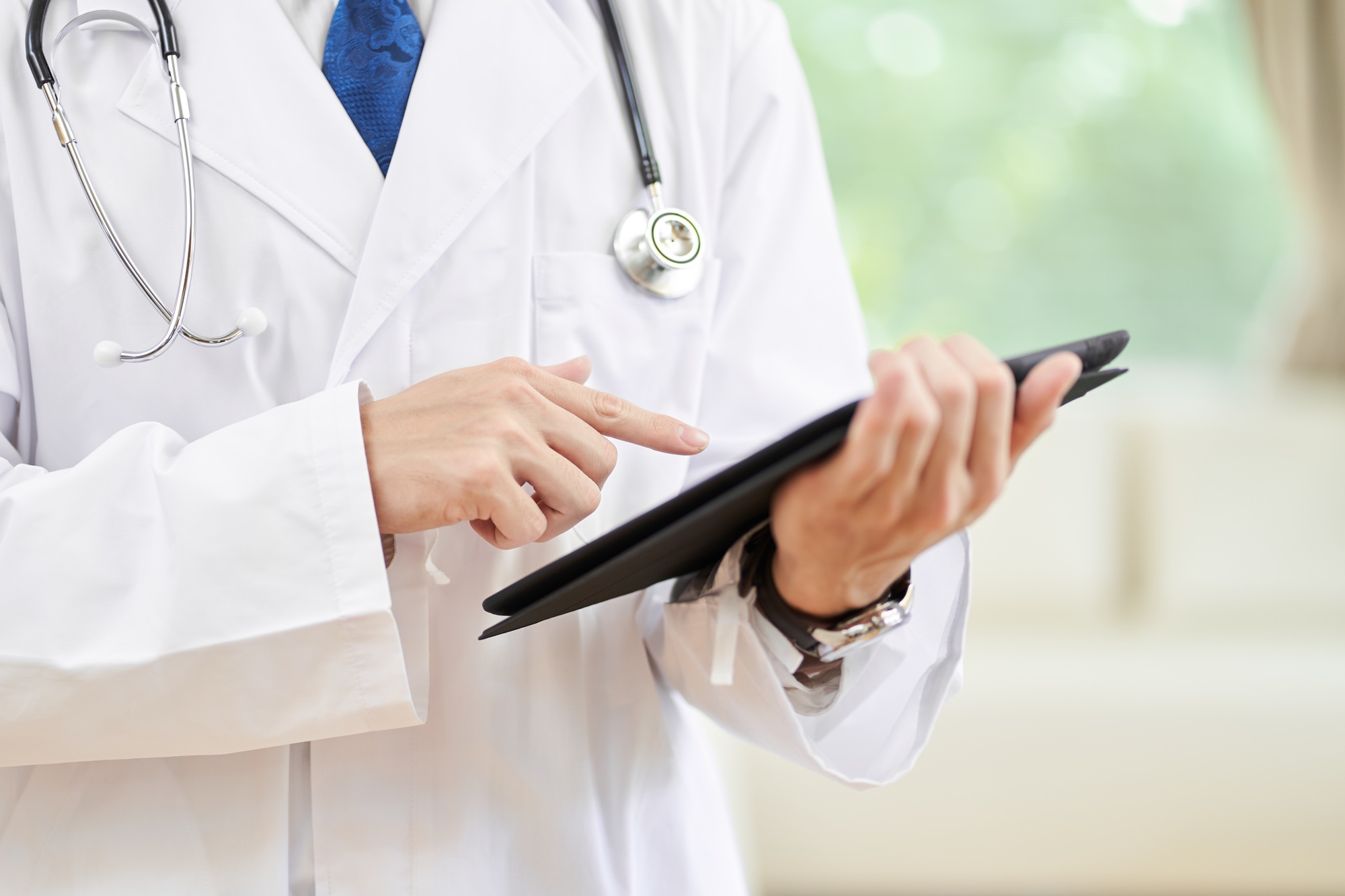Hands of a male doctor with an electronic medical record